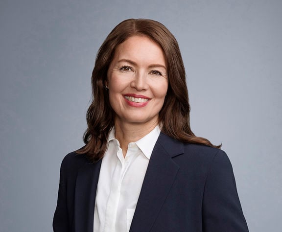 Formal portrait of Sampo plc’s Chief Legal Officer, Tiina Halmesmäki, wearing a dark suit and smiling at the camera.