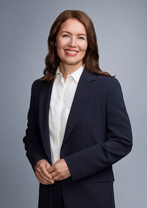 Formal portrait of Sampo plc’s Chief Legal Officer, Tiina Halmesmäki, wearing a dark suit and smiling at the camera.