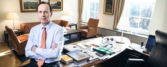 Sampo Group CEO Kari Stadigh sitting casually with arms crossed, leaning against the office desk.